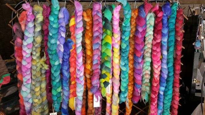 Multicoloured plaits of hand-dyed wool hanging on a display