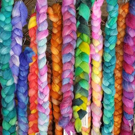 A row of plaits of brightly-coloured wool fibre tops