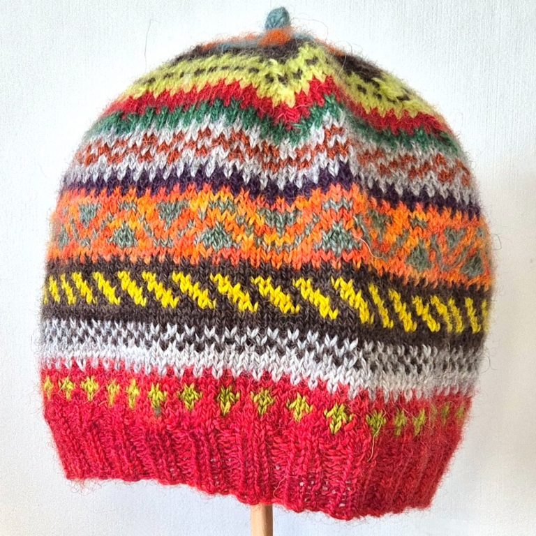 Fair Isle hat with patterned stripes of red, beige, brown, orange and yellow