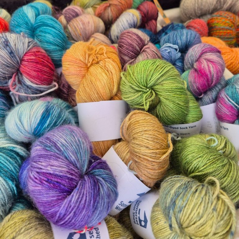 A basket of skeins of brightly-coloured sock yarn in purple, gold, green, pink and blue